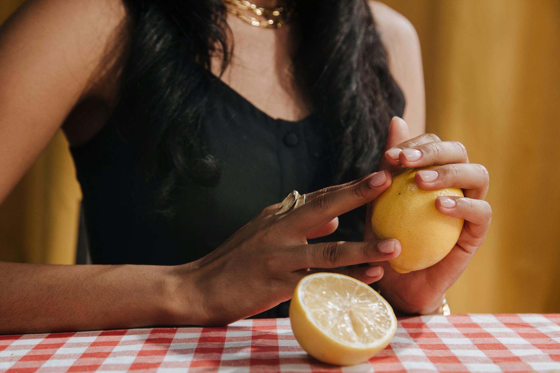 A hand holding a fresh lemon against a yellow background, representing clarity and freshness.