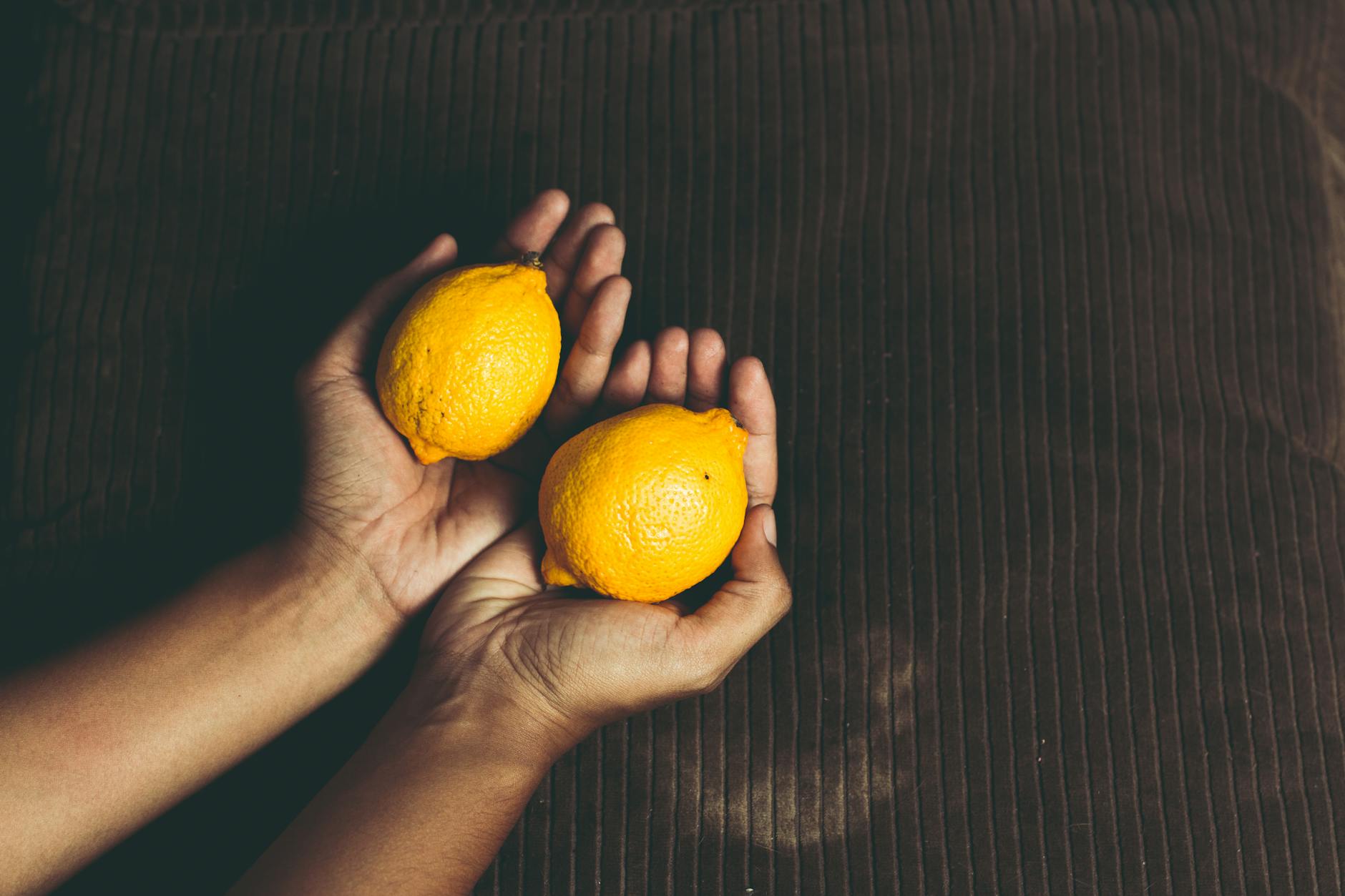 Two fresh lemons held gently in cupped hands, symbolizing care and sensitivity