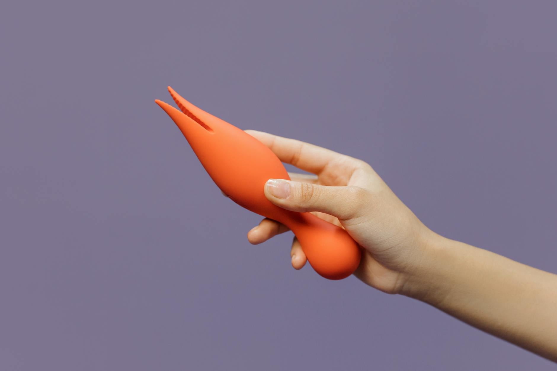 A hand holding a compact lemon vibrator against a minimalist purple backdrop, emphasizing portability and modern design.