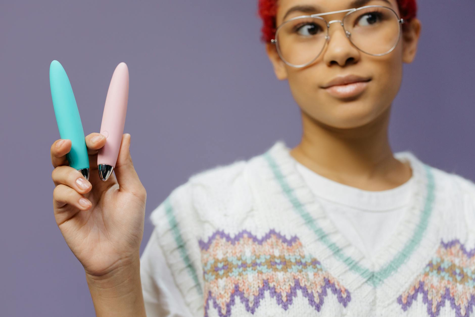 Woman holding a colorful clitoral vibrator against a purple background, symbolizing personal pleasure and relationship intimacy