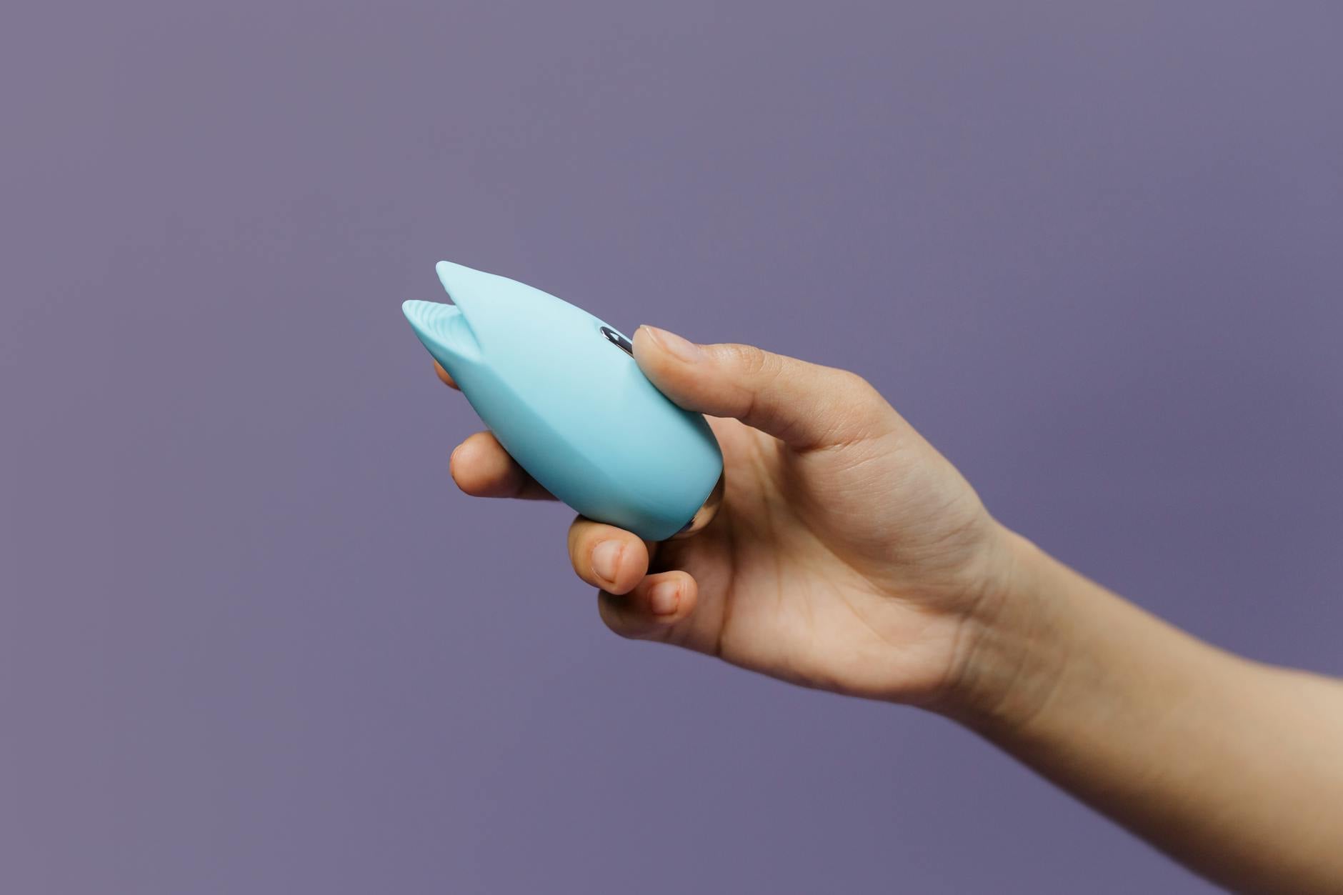 Hands holding a blue silicone vibrator, representing shared pleasure and intimacy