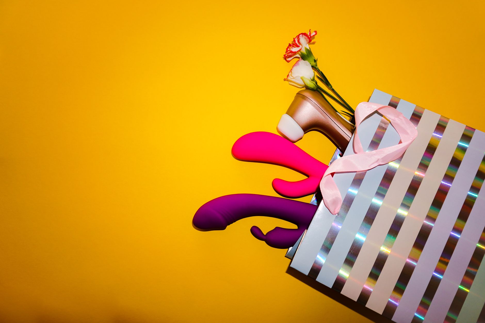 Colorful arrangement of vibrators and flowers on a bright yellow background